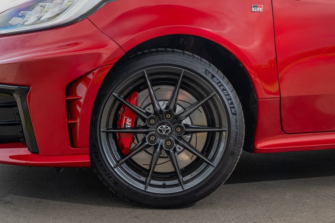 Roda de liga leve do Toyota GR Yaris escurecida com pinça de freio pintada de vermelho