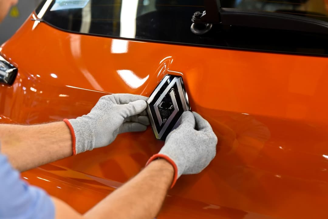 Funcionário coocando símbolo da Renault em carro